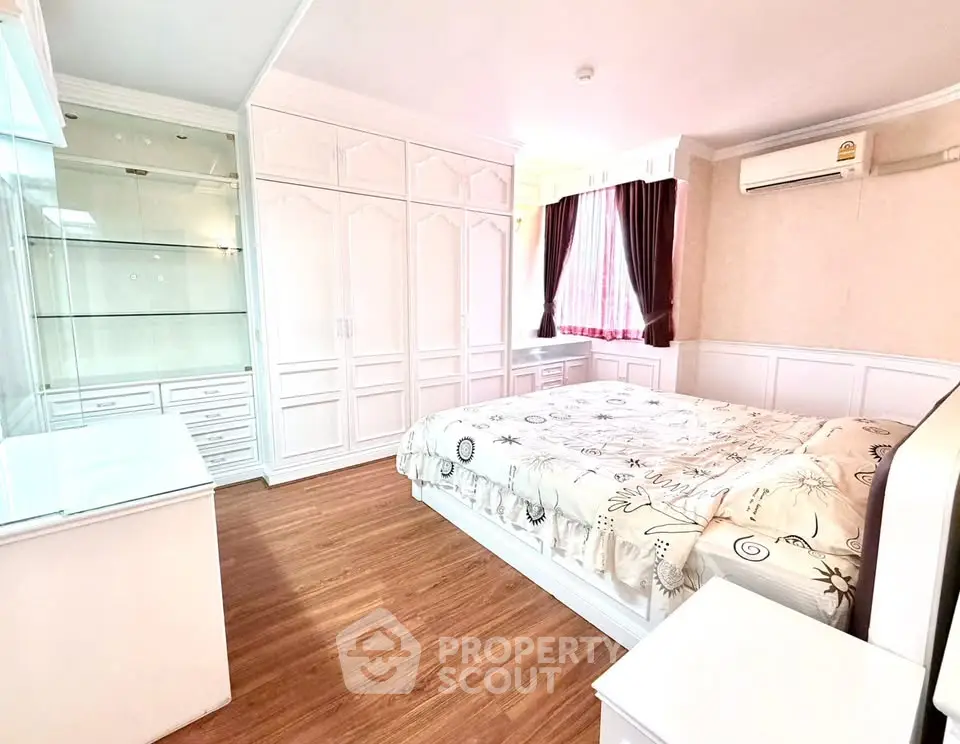 Spacious bedroom with elegant white cabinetry and hardwood floors