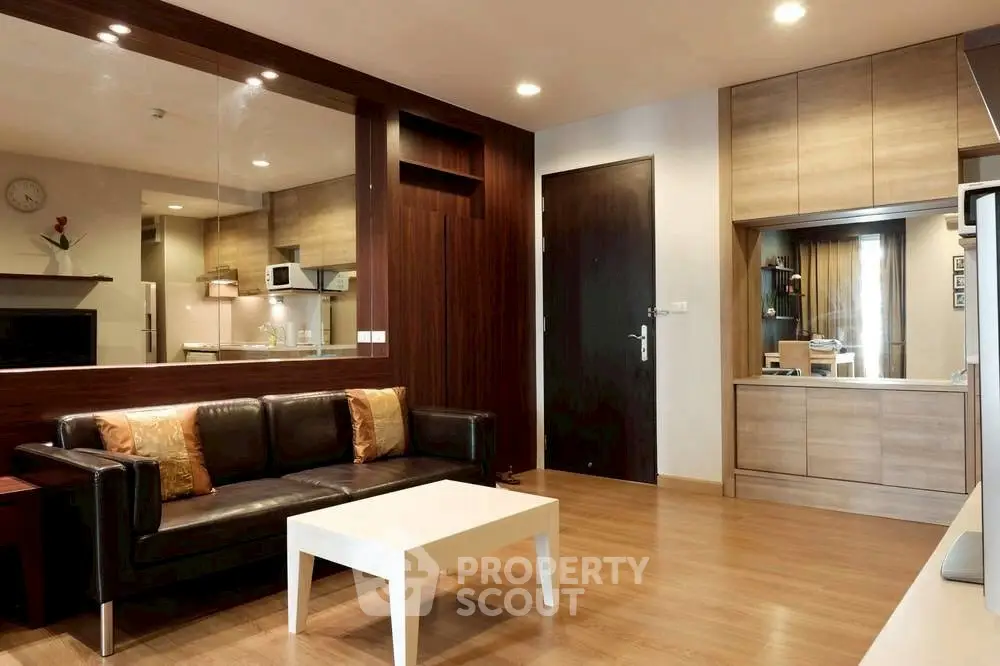 Modern living room with sleek wooden accents and open kitchen layout.