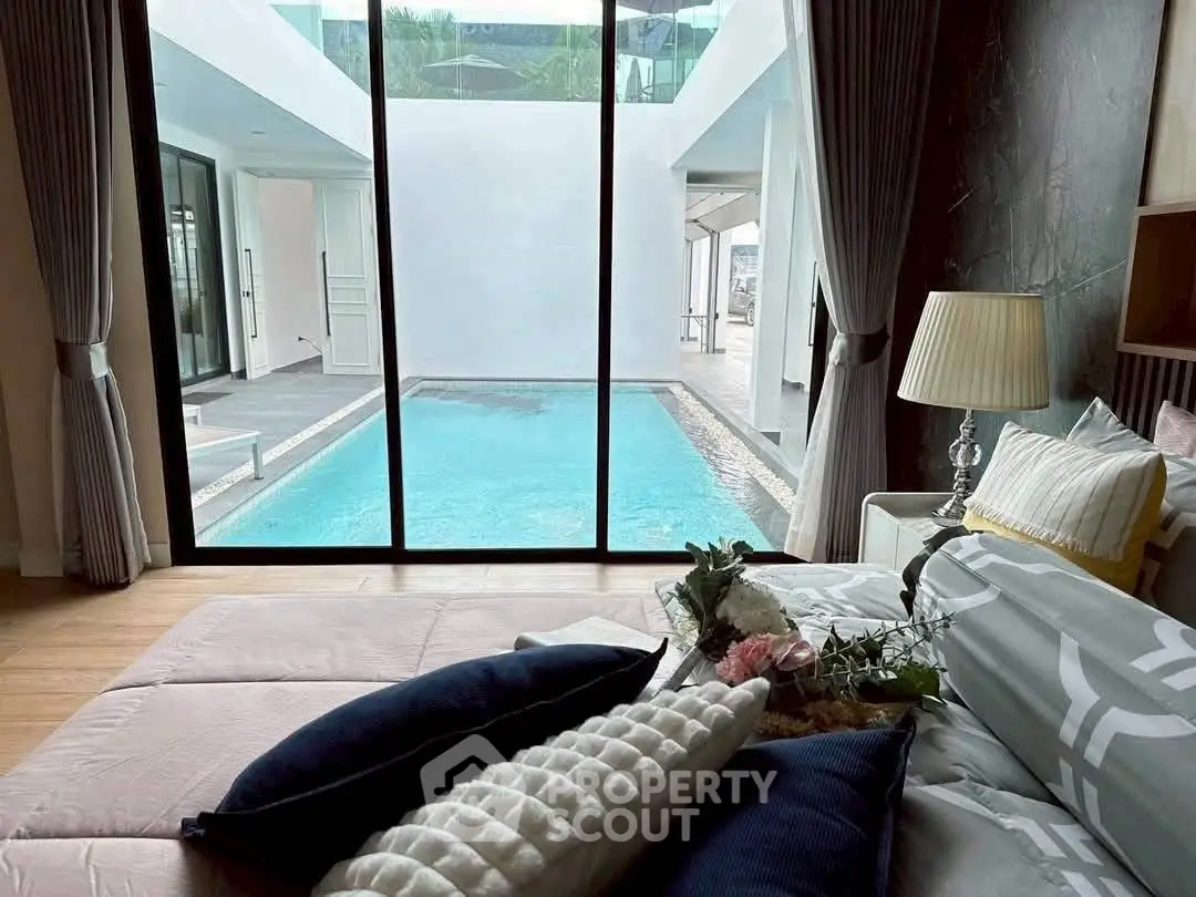 Luxurious bedroom with pool view, elegant decor, and abundant natural light.