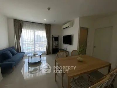 Modern living room with stylish furniture and large window offering city views.