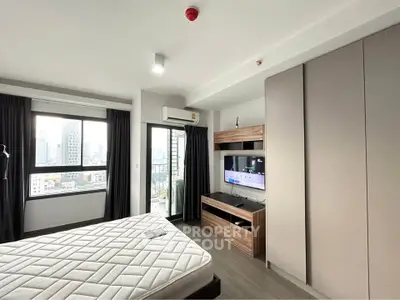 Modern bedroom with city view, featuring a large window, built-in wardrobe, and wall-mounted TV.