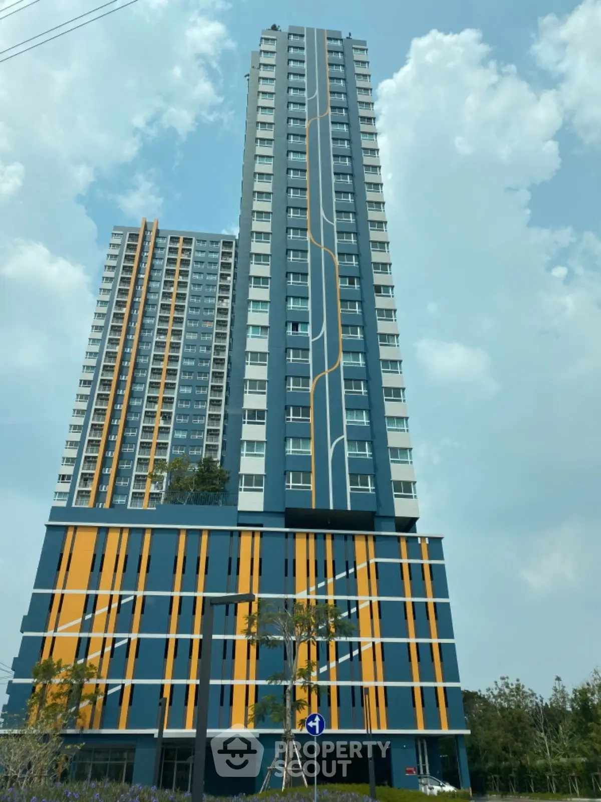 Modern high-rise building with unique facade design and lush surroundings.