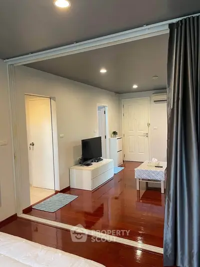Modern living room with sleek design and wooden flooring, featuring a TV unit and stylish decor.