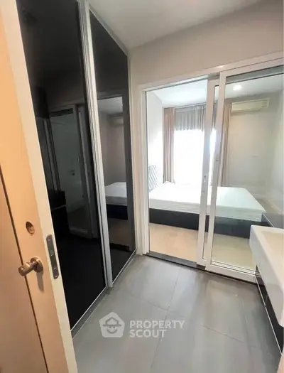Modern bedroom with sliding glass doors and mirrored closet in a stylish apartment.