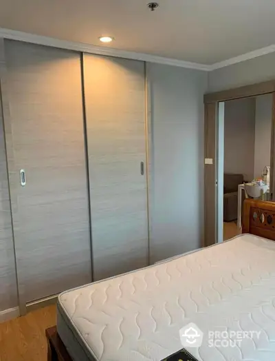 Cozy bedroom with a large bed and spacious built-in wardrobe, featuring warm lighting and a serene ambiance, perfect for relaxation.