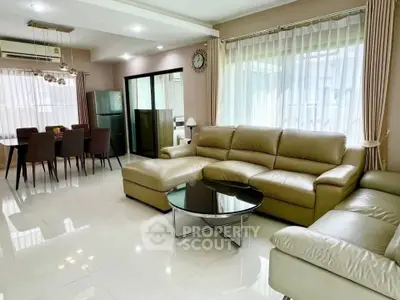 Spacious modern living room with elegant leather sofa and dining area, perfect for family gatherings.