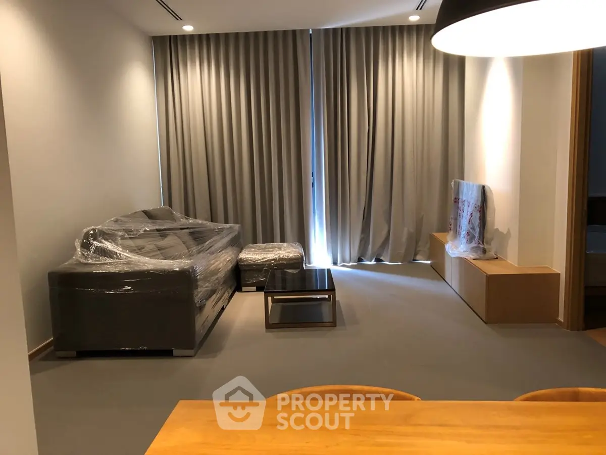 Modern living room with sleek furniture and floor-to-ceiling curtains in a stylish apartment.