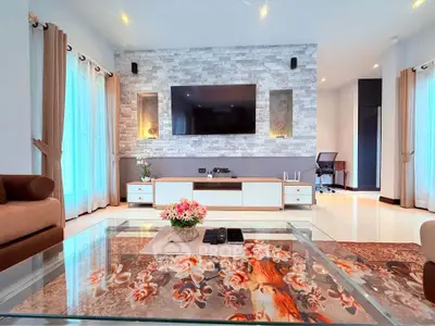 Spacious modern living room with elegant decor and large TV, perfect for relaxation and entertainment.