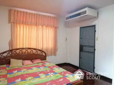 Cozy bedroom with colorful bedding and air conditioning, perfect for comfort and relaxation.