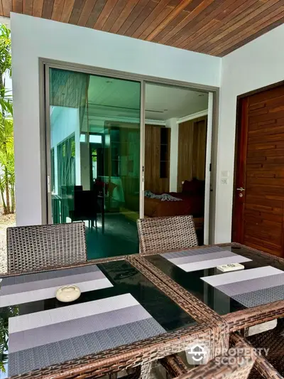 Stylish outdoor dining area with glass doors leading to modern interior