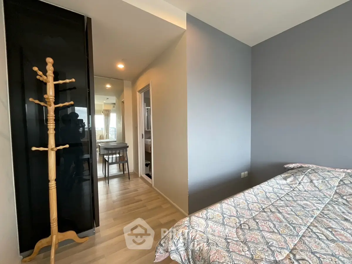 Modern bedroom with stylish decor and wooden flooring, featuring a cozy bed and elegant coat rack.
