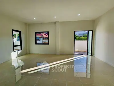 Spacious sunlit living room with tiled flooring and large windows