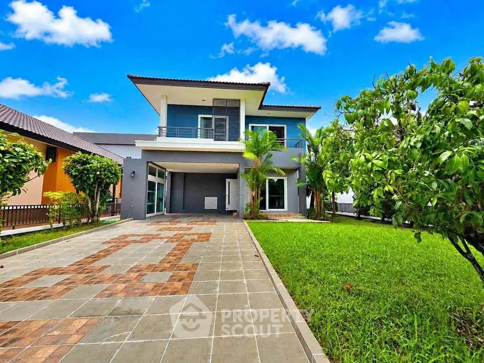 Stunning modern two-story house with lush garden and spacious driveway under a clear blue sky.