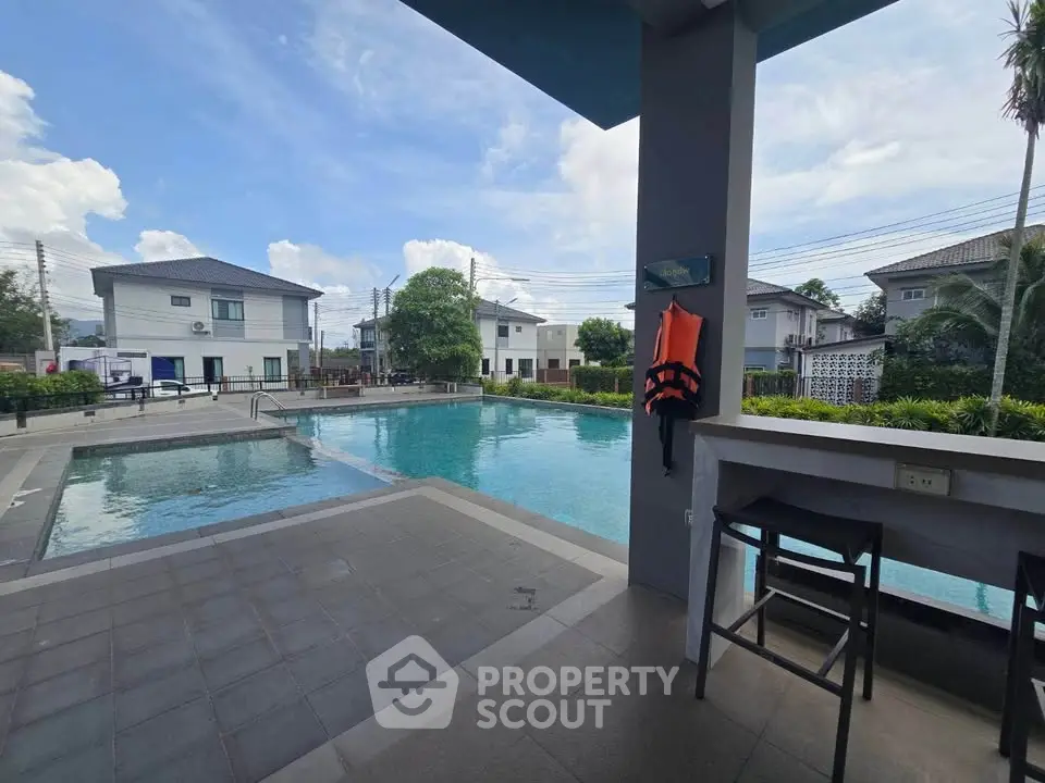 Luxurious residential pool area with modern seating and lush greenery, perfect for relaxation and leisure.