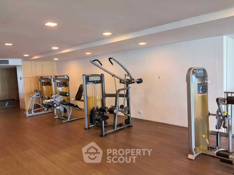 Spacious gym with modern exercise equipment in upscale residential building.