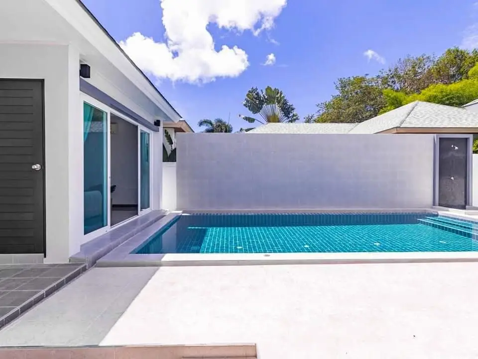 Luxurious modern villa with private pool and spacious patio under clear blue sky.