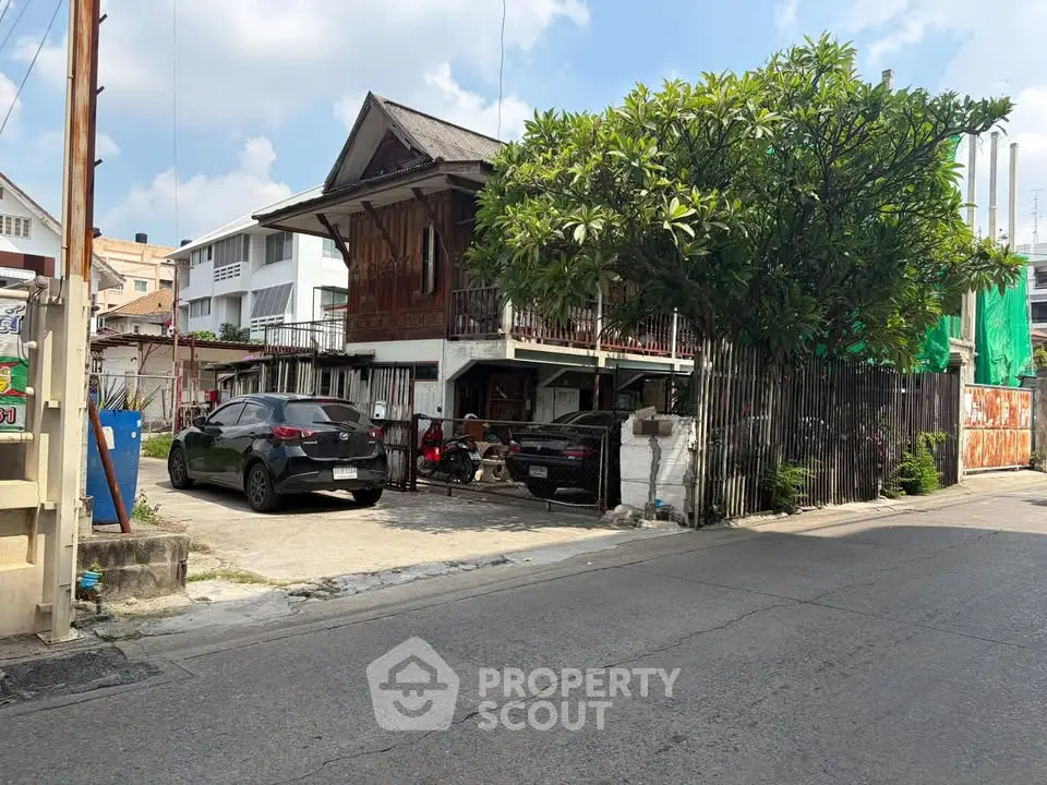 Charming traditional wooden house with lush greenery and ample parking space in a serene neighborhood.