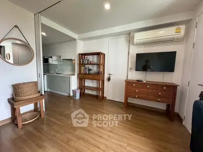 Charming living room with wooden flooring and modern decor, featuring a compact kitchen area.