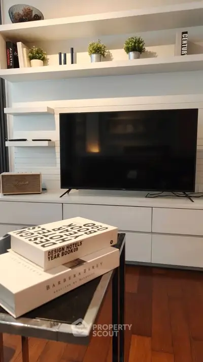 Modern living room with sleek TV, stylish shelves, and hardwood floors.