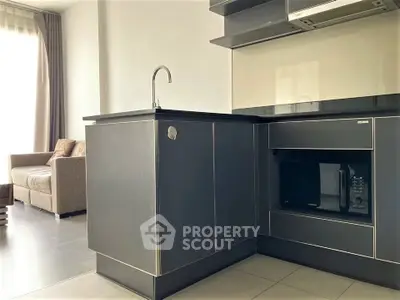Modern kitchen with sleek black cabinetry and open layout adjacent to cozy living area.