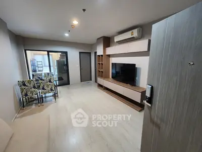 Spacious living room with modern furnishings, sleek built-in entertainment unit, and ample natural light from balcony doors.