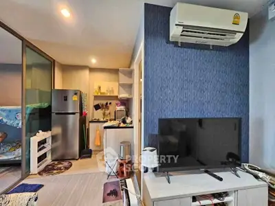 Modern living room with open kitchen, featuring air conditioning and sleek appliances.