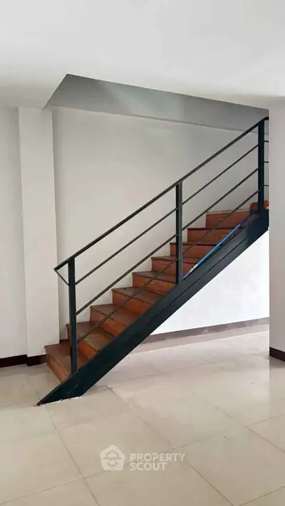 Modern interior staircase with sleek metal railing and wooden steps in a contemporary home.
