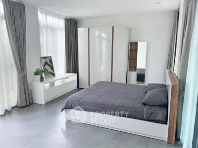 Spacious modern bedroom with sleek furniture and large windows for natural light.