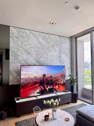 Luxurious living room with marble accent wall and large TV, offering stunning city views through floor-to-ceiling windows.