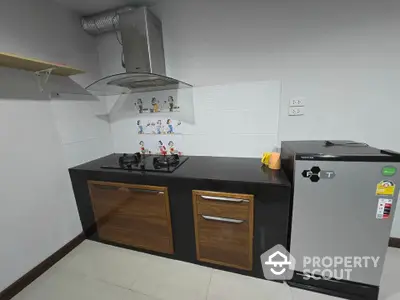 Modern kitchen with gas stove and compact fridge in sleek apartment