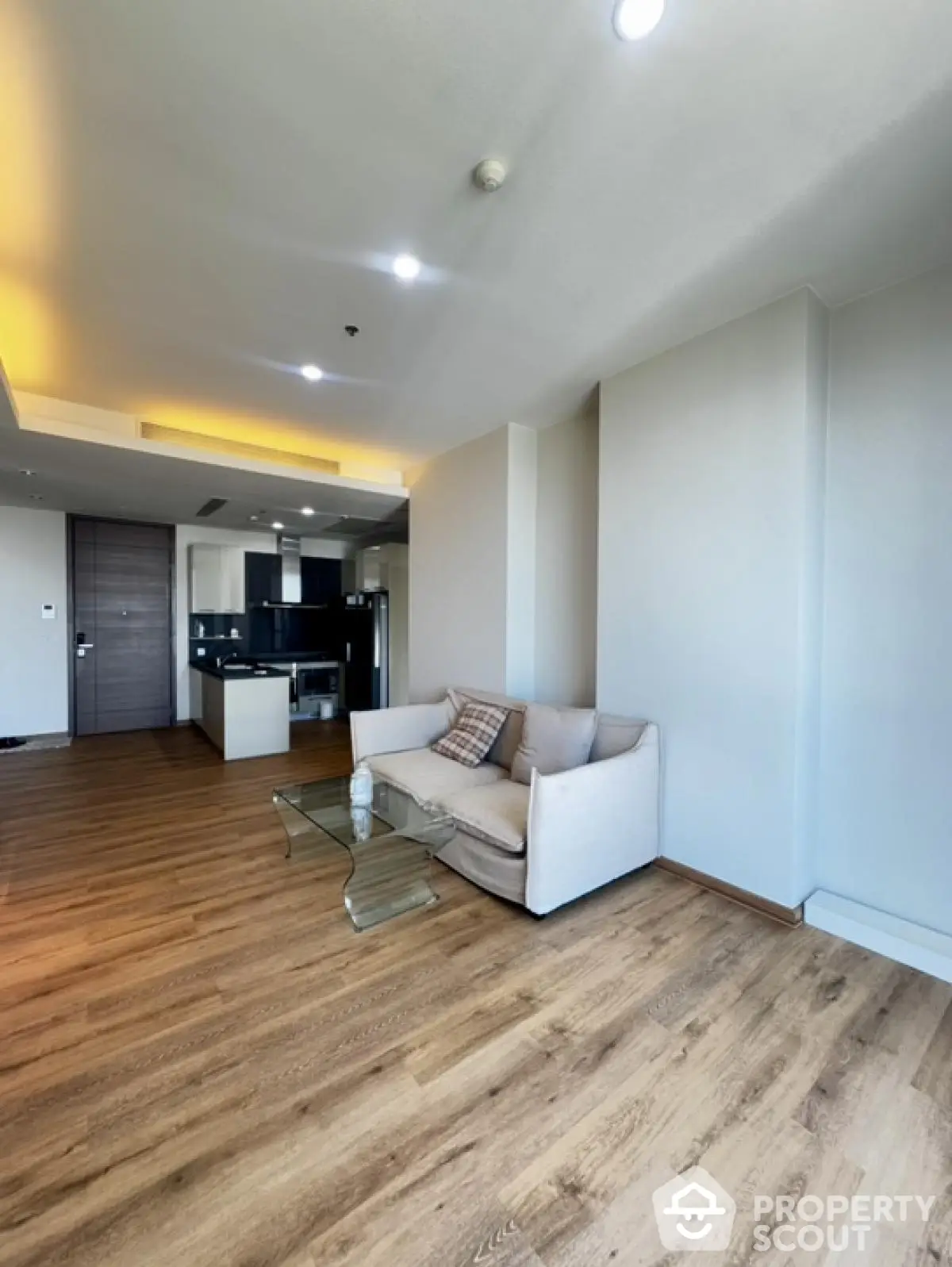 Modern living room with open kitchen and wooden flooring in a stylish apartment.