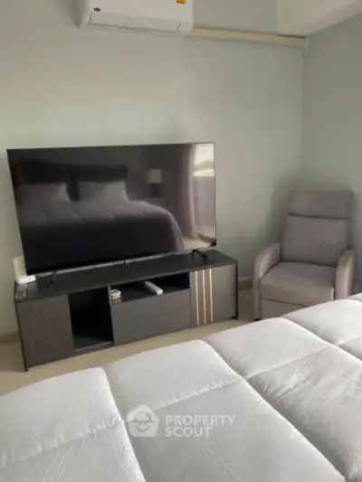 Modern bedroom with sleek TV setup and comfortable armchair