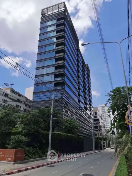 Modern high-rise building with sleek glass facade on a sunny day.