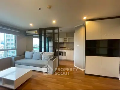 Modern living room with open kitchen in high-rise apartment, featuring sleek furniture and city view.