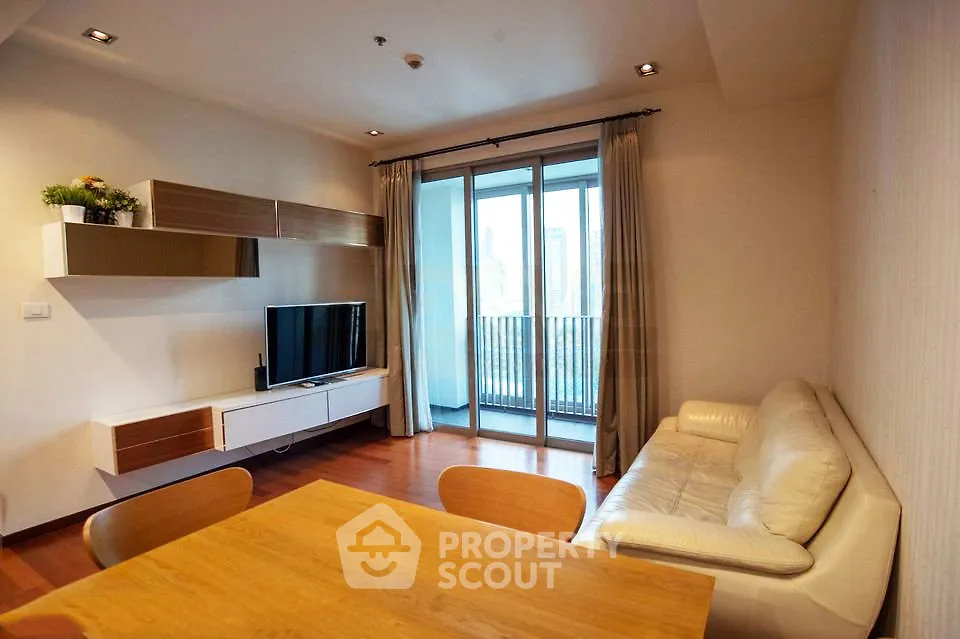 Modern living room with balcony view, featuring sleek furniture and natural light.