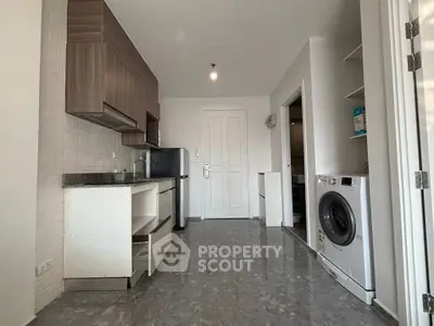 Modern kitchen with washing machine and sleek cabinetry in open layout apartment.