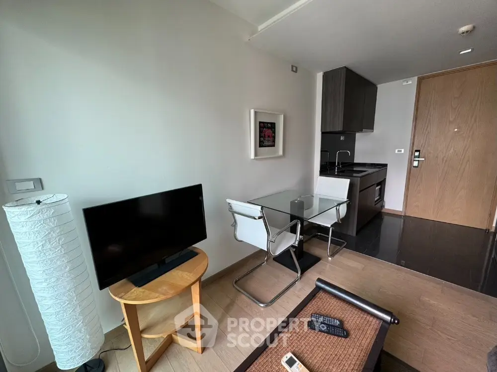 Modern studio apartment with compact kitchen and cozy living area featuring a TV and dining table.