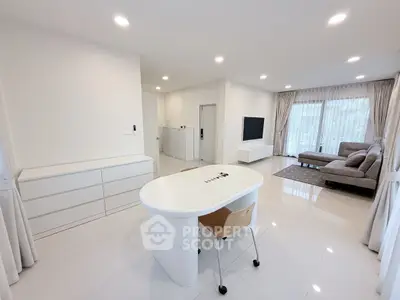 Spacious modern living room with sleek white furniture and large windows for natural light.