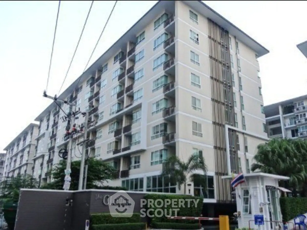 Modern condominium building with lush greenery and secure entrance in prime location.