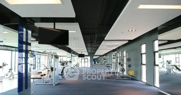 Spacious modern gym with state-of-the-art equipment and large windows for natural light.