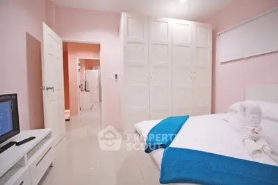 Charming bedroom with modern white furniture and soft pink walls, perfect for relaxation.