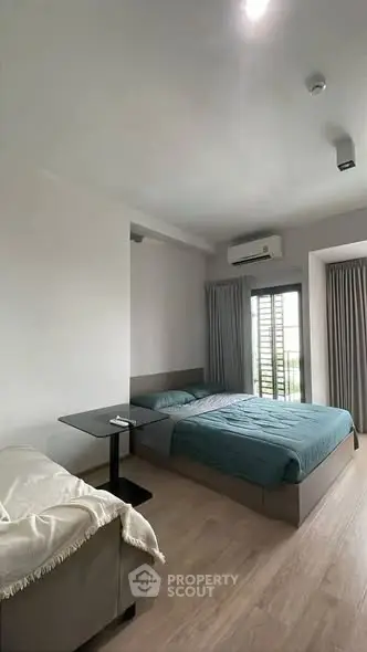 Modern bedroom with stylish decor and natural light, featuring a cozy bed and sleek furnishings.