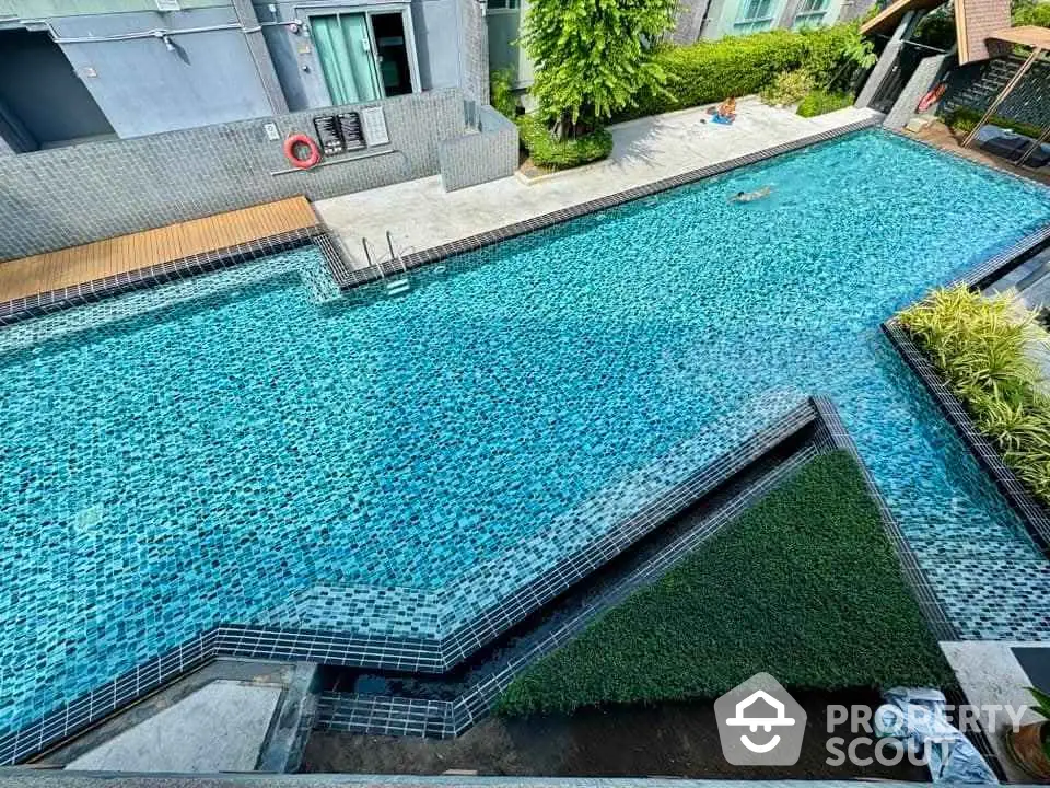 Luxurious outdoor swimming pool with modern design and lush greenery in a high-end residential complex.