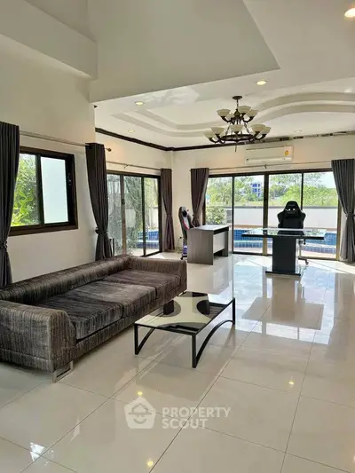 Spacious living room with modern furniture and pool view, perfect for relaxation and entertainment.
