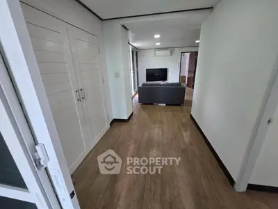 Spacious living room with modern decor and wooden flooring, featuring a sleek TV setup and comfortable seating.