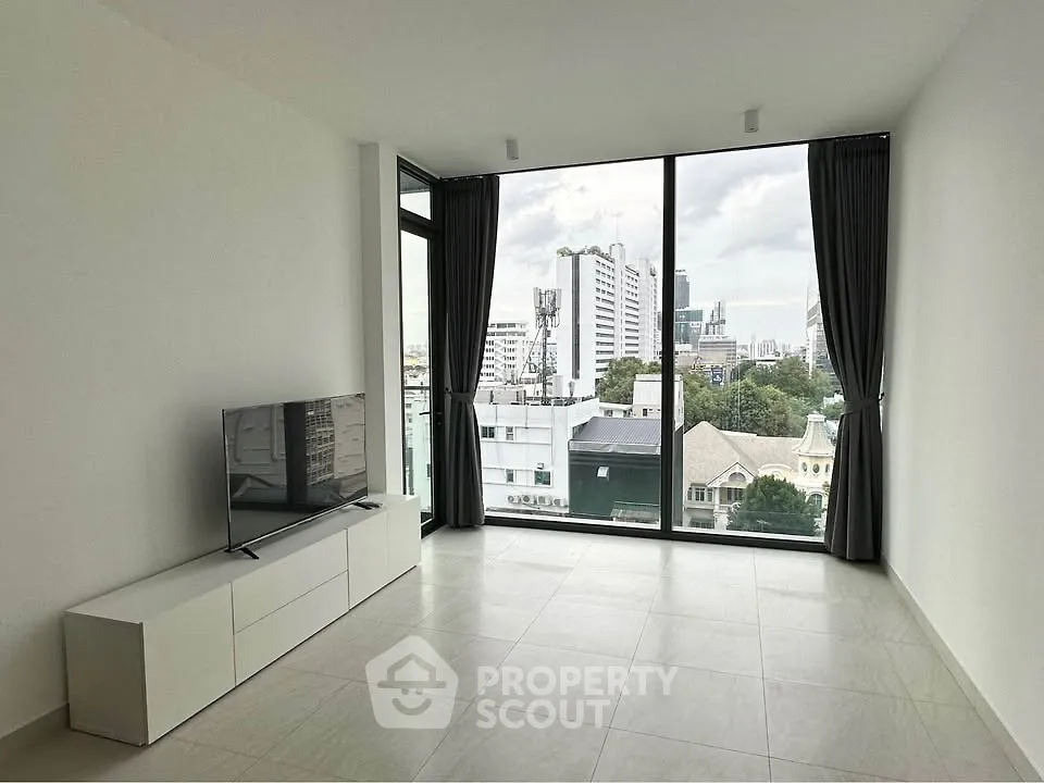 Modern living room with large windows and city view, featuring sleek TV stand and minimalist design.