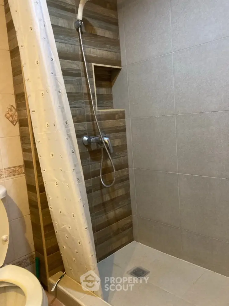 Modern bathroom with tiled shower and curtain, featuring neutral tones.