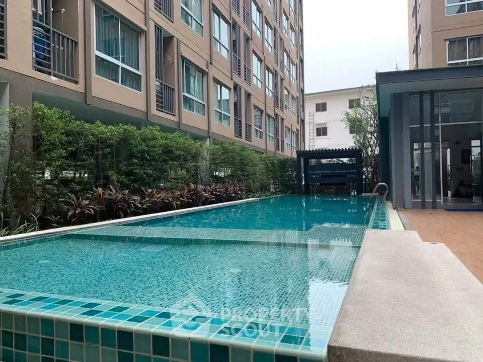 Modern apartment complex with a sleek outdoor swimming pool and lush greenery.