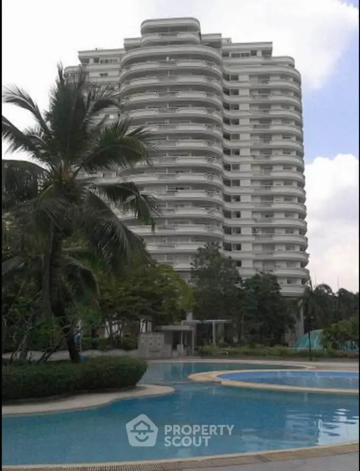 Luxurious high-rise building with stunning pool and lush greenery, perfect for upscale living.