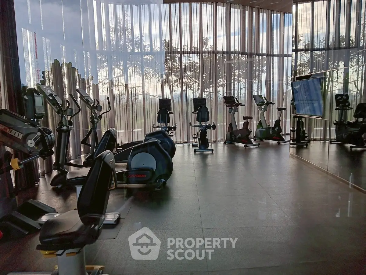 Modern gym with state-of-the-art equipment and floor-to-ceiling windows offering scenic views.